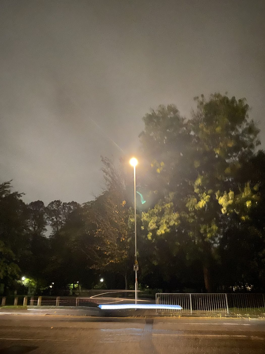 A street lamp at night with streaks of passing light