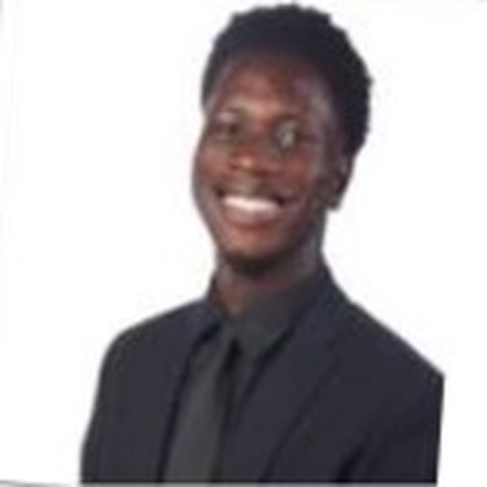 Kwame smiling in a black suit and tie