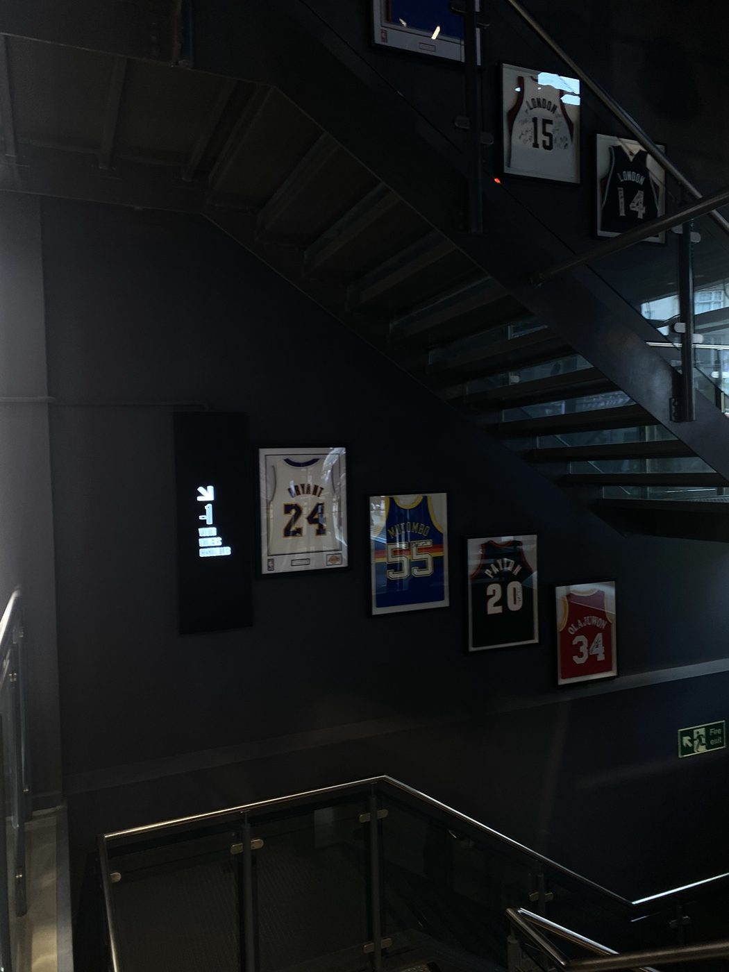 Framed basketball jerseys lining a dark staircase