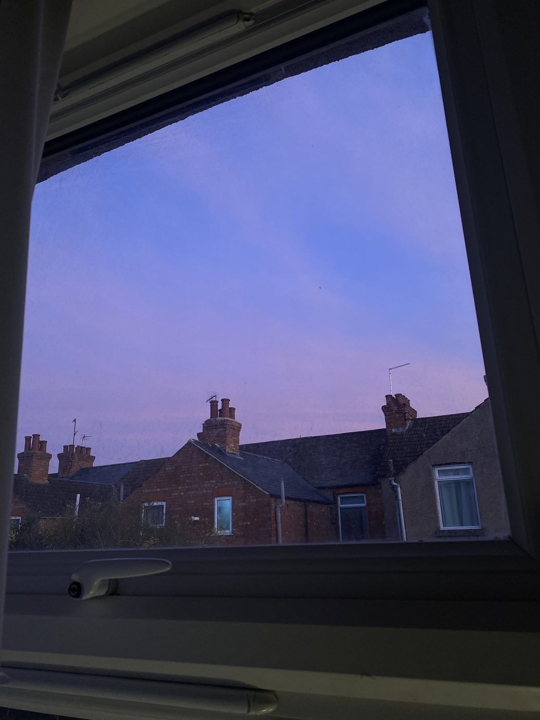 A purple evening sky over brick rooftops and chimneys