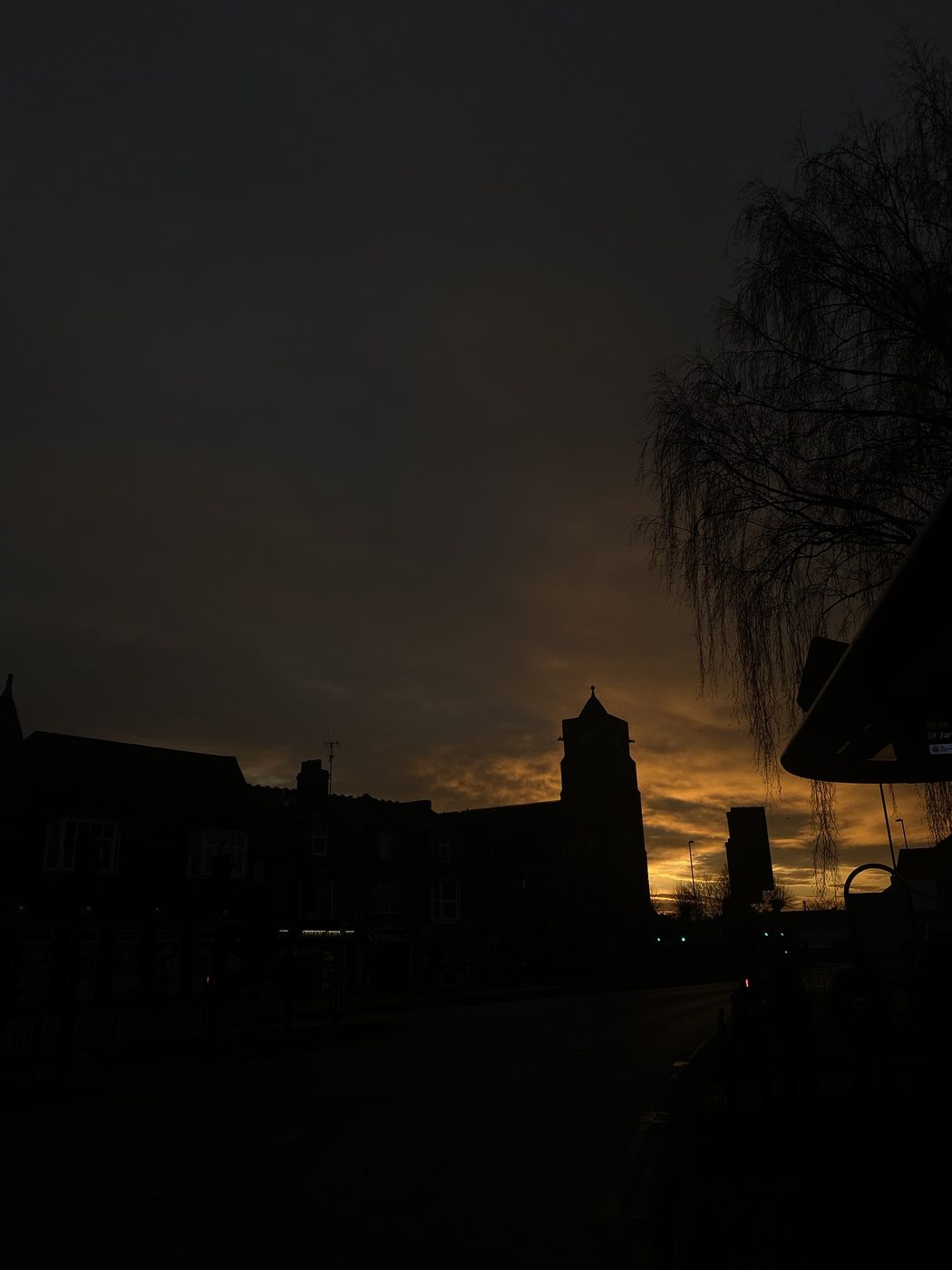 A church tower silhouetted against an orange sky
